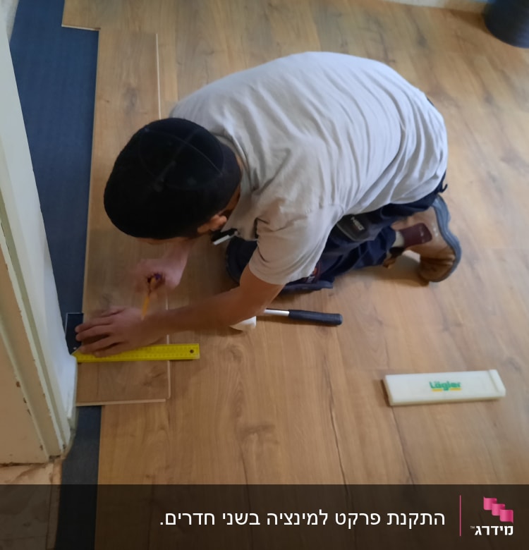 אדם מתקין פרקט בעזרת סרגל ועיפרון